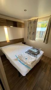 Cette chambre comprend un grand lit et une fenêtre. dans l'établissement Mobil home Onesse et Laharie RML Newcamp "le bois des Landes", à Onesse-et-Laharie