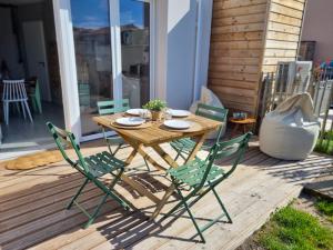 a wooden table and chairs on a deck at La Cabane de Jeanne ~ 10 minutes à pied de l'océan in Mimizan
