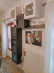 a kitchen with white cabinets and a painting on the wall at Vien mequé in Città di Castello