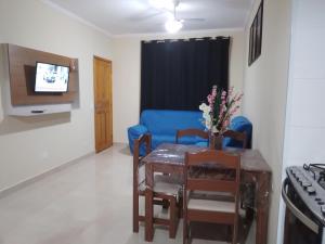 uma sala de estar com uma mesa e um sofá azul em Apto Alto Estilo Maranduba Ubatuba em Ubatuba