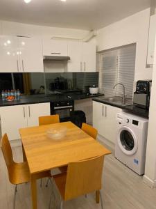 une cuisine avec une table et des chaises ainsi qu'un lave-linge dans l'établissement (023) Lovely 2 bedroom house London, à Londres