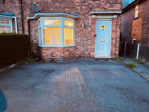 a brick house with a blue door and a driveway at Inviting 3 -Bed House in Birmingham in Birmingham