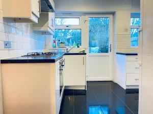 a kitchen with white cabinets and black counter tops at Inviting 3 -Bed House in Birmingham in Birmingham