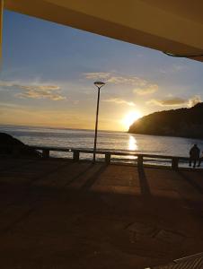un tramonto sull'oceano con un lampione di Encosta Serra Lagoa do Fogo 1/4 da Casa Do Monte a Vila Franca do Campo