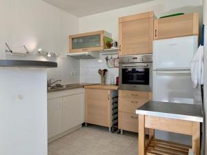 eine Küche mit weißen Geräten und Holzschränken in der Unterkunft Appartement Mèze, 2 pièces, 4 personnes - FR-1-604-36 in Mèze