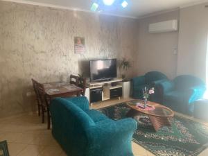 a living room with blue chairs and a television at Guest House Fier in Fier