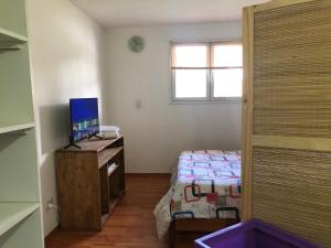 Habitación pequeña con cama y escritorio con ordenador. en Quilmeña-al-Sur Departamento 1 en Esquel