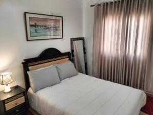 - une chambre avec un lit blanc et une fenêtre dans l'établissement Appartement calme et confortable, à Al Ghar
