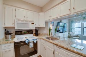 a kitchen with white cabinets and a stove and a sink at Vibrant Gulf Shores Getaway with Pool and Beach Access in Gulf Shores