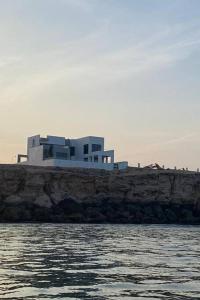 une maison assise au sommet d'une falaise à côté de l'eau dans l'établissement Wadi Shab/Fins Villa, à Fins