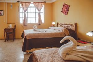 una camera con 2 letti e un cigno sul letto di Hotel Shinula a Huehuetenango