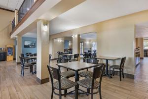 a restaurant with tables and chairs and a staircase at Best Western International Speedway Hotel in Daytona Beach