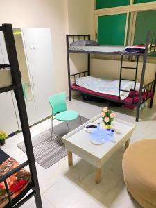 MBZ - Nice Bed Space "MEN" في أبوظبي: غرفة بسريرين بطابقين وطاولة وكراسي