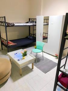 Cette chambre comprend 2 lits superposés, une table et des chaises. dans l'établissement MBZ - Nice Bed Space "MEN", à Abu Dhabi