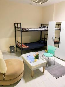 a room with two bunk beds and a coffee table at MBZ - Nice Bed Space "MEN" in Abu Dhabi