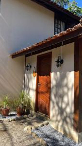 una casa con una puerta de madera y algunas plantas en POUSADA MAISON MAUÁ en Visconde De Maua
