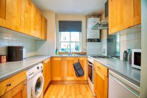 a kitchen with wooden cabinets and a washing machine at 2 Bed Camden Mews in London