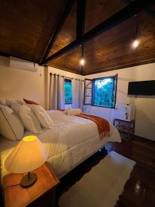 ein Schlafzimmer mit einem Bett und einer Lampe auf einem Tisch in der Unterkunft POUSADA MAISON MAUÁ in Visconde De Maua