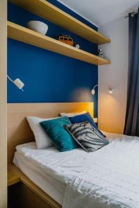 um quarto com uma parede azul e uma cama com almofadas em Warsaw Concierge Kruczkowskiego em Varsóvia