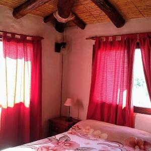 a bedroom with red curtains and a bed with a lamp at Hotel La Herencia in Tilcara