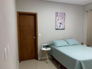 1 dormitorio con cama, mesa y puerta en Casa bem aconchegante! en Ubatuba