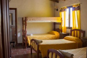 two bunk beds in a room with yellow curtains at Hotel La Herencia in Tilcara
