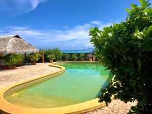 a swimming pool in the middle of a resort at Superbe bord de mer, accès lagon et piscine privée in Paea