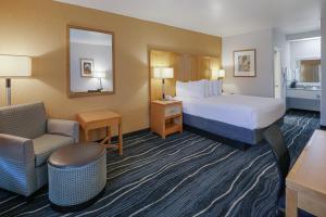 a hotel room with a bed and a chair at Ramada by Wyndham Costa Mesa/Newport Beach in Costa Mesa +60 photos
