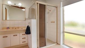 a bathroom with a shower and a sink and a mirror at 41 Collins Street Merimbula in Merimbula +19 photos