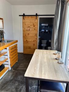 a kitchen with a wooden table and a door at Heart of Ruta Del Vino, Cozy Casitas Pan y Vino! in Valle de Guadalupe