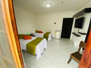 a hotel room with two beds and a tv at Carpao Lodging Galapagos in Puerto Ayora
