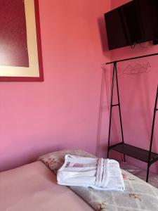 Una cama con una pared rosa con una toalla. en Casa Rosa Hotel & Spa en San Cristóbal de Las Casas