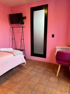 Habitación rosa con cama y TV en Casa Rosa Hotel & Spa en San Cristóbal de Las Casas