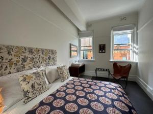 1 dormitorio con 1 cama, 1 silla y 2 ventanas en The Resch House en Sídney