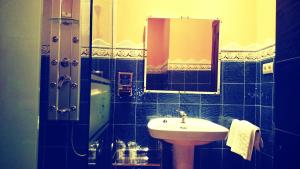 Baño de azulejos azules con lavabo y espejo en El Huésped del Sevillano AR, en Lagartera