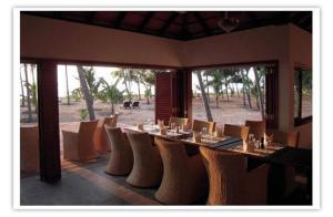 a dining room with a table and chairs with a view at Kanan Beach Resort in Nīleshwar