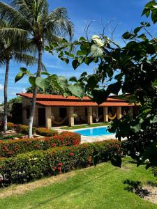 un complejo con una piscina y una palmera en Pousada Solar das Fontes, en Beberibe