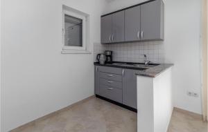 a kitchen with gray cabinets and a sink and a window at Lovely Apartment In Ribarica - Karlobag in Matić Podi