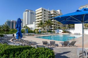 basen z krzesłami i niebieskim parasolem w obiekcie Decoplage Paradise - Unit B w Miami Beach