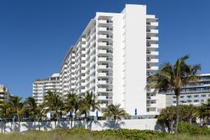 wysoki biały budynek z palmami przed nim w obiekcie Decoplage Paradise - Unit B w Miami Beach