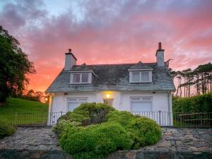een wit huis met een zonsondergang op de achtergrond bij Balnowlart Lodge in Ballantrae