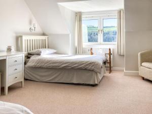 a bedroom with a bed and a window and a chair at Balnowlart Lodge in Ballantrae