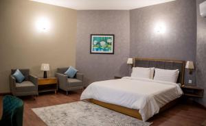 um quarto com uma cama grande e 2 cadeiras em Hillside Residence E-7 by Paramount Hospitality em Islamabad