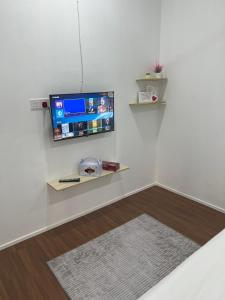 uma sala de estar com televisão numa parede branca em A’Casa Cottage em Kuala Terengganu