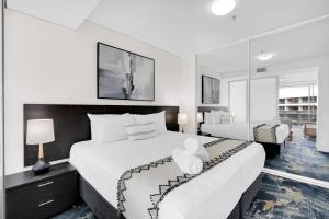 a hotel room with two beds and a mirror at City Living at Harbour Lights in Cairns