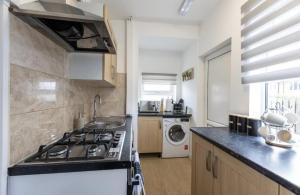 a kitchen with a stove and a sink at Luxury 3 bedroomed home in Kettering