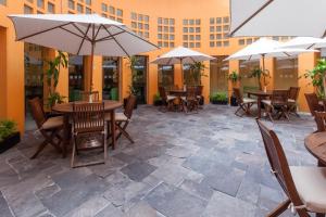 un patio con tavoli, sedie e ombrelloni di Holiday Inn Puebla Finsa by IHG a Puebla