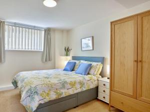 a bedroom with a bed and a wooden cabinet at Polgew Apartment in Marazion