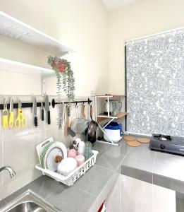 uma cozinha com lavatório e utensílios na parede em Homestay Akasia 12 em Seri Iskandar