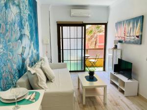 a living room with a white couch and a tv at Salvador Cuyas "Apartamento el Mar" in Las Palmas de Gran Canaria